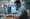 Profissional trabalhando em um escritório, analisando gráficos de crescimento e desempenho em dois monitores com chuva ao fundo, representando o impacto do Blackbox AI na gestão de dados.