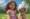 Menina de cerca de 3 anos com vestido rosa brincando com um Labrador em um parque radiante, capturando um momento alegre e natural.